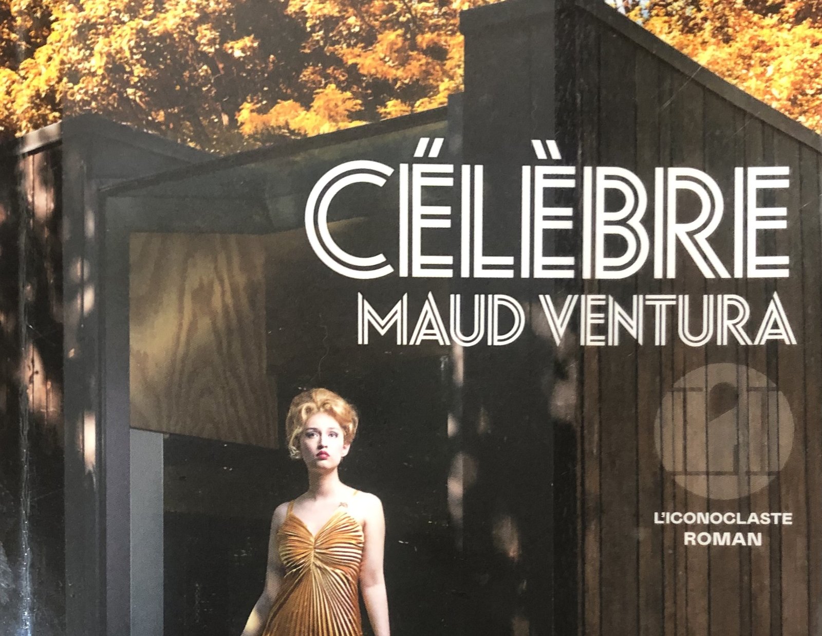 Extrait de la Couverture de Célèbre de Maud Ventura : un star en robe lamée dorée devant une cabane