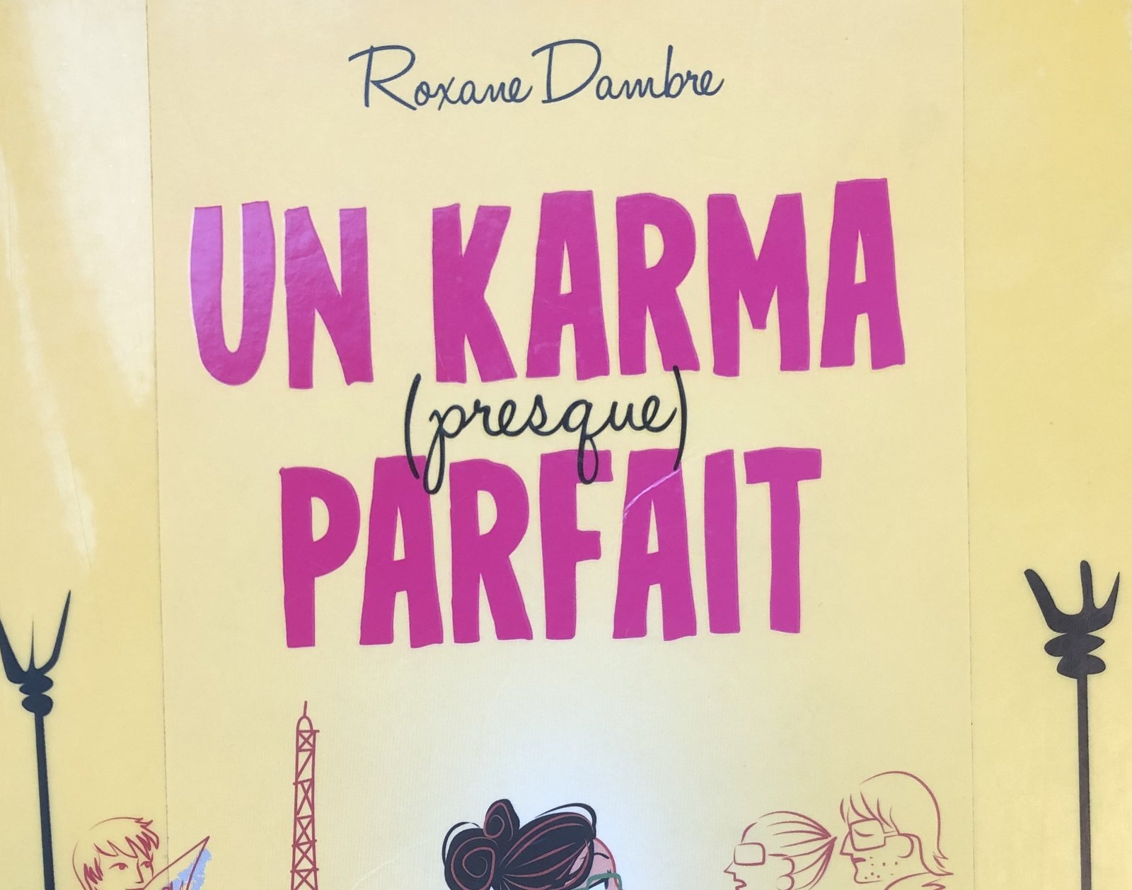 Extrait de la Couverture de Un karma (presque) parfait de Roxane Dambre : un dessin d'une jeune femme qui traverse Paris en vélo, avec une pochette de documents.