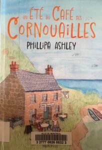 Couverture de Un été aux Cornouailles de Phillipa Ashley : un café dans une vieille maisonnette en pierres au bord de la mer.