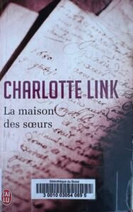 Couverture de La maison des soeurs par Charlotte Link, avec les pages d'un manuscrit en fond