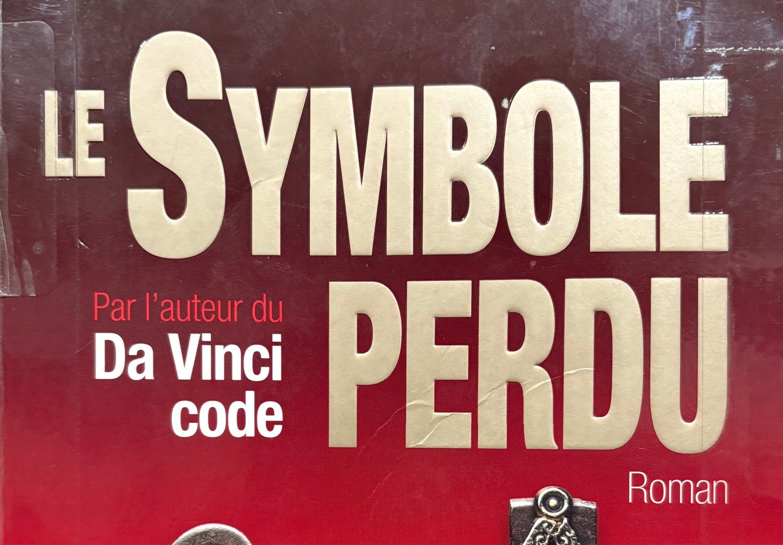 Extrait de la Couverture de Le symbole perdu par Dan Brown : le toit du Capitole surmonté d'une clé forgée avec un symbole maçonnique sur un fond rouge
