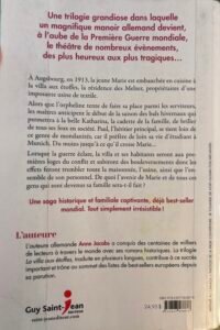 Quatrième de la Couverture de La villa aux étoffes, Tome 1, L'héritage, d'Anne Jacobs. Une jeune femme de dos regarde une belle maison au fond de l'allée d'un parc.